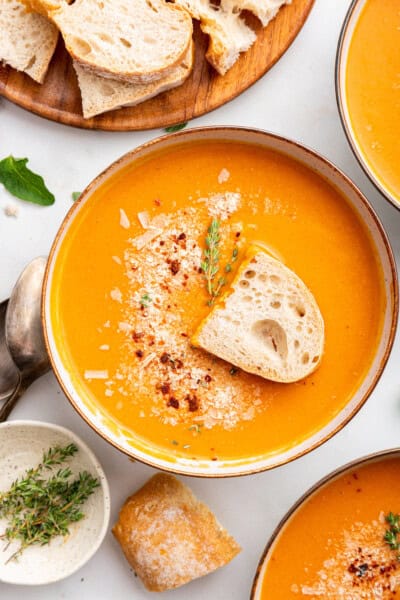 Tomato bisque in a bowl with a piece of toast on top.