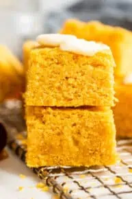 Two pieces of vegan pumpkin cornbread on top of each other, with a pat of butter on top
