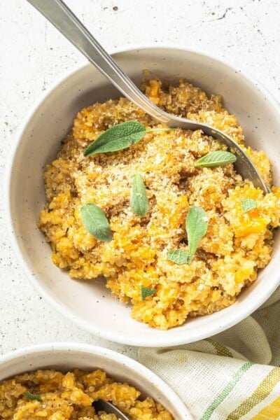 A bowl of butternut squash quinoa risotto garnished with sage.