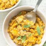 Close up overhead view of two bowls of butternut squash quinoa risotto garnished with sage.