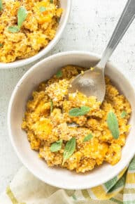 Close up overhead view of two bowls of butternut squash quinoa risotto garnished with sage.