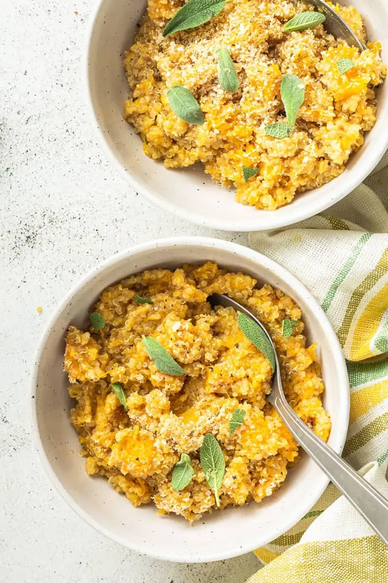 Overhead view of two bowls of butternut squash quinoa risotto garnished with sage.