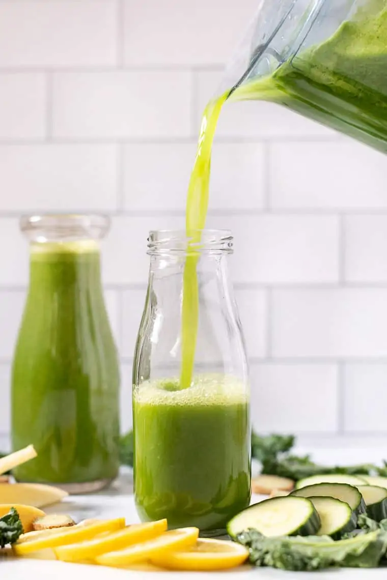 pouring green juice with ginger into a glass