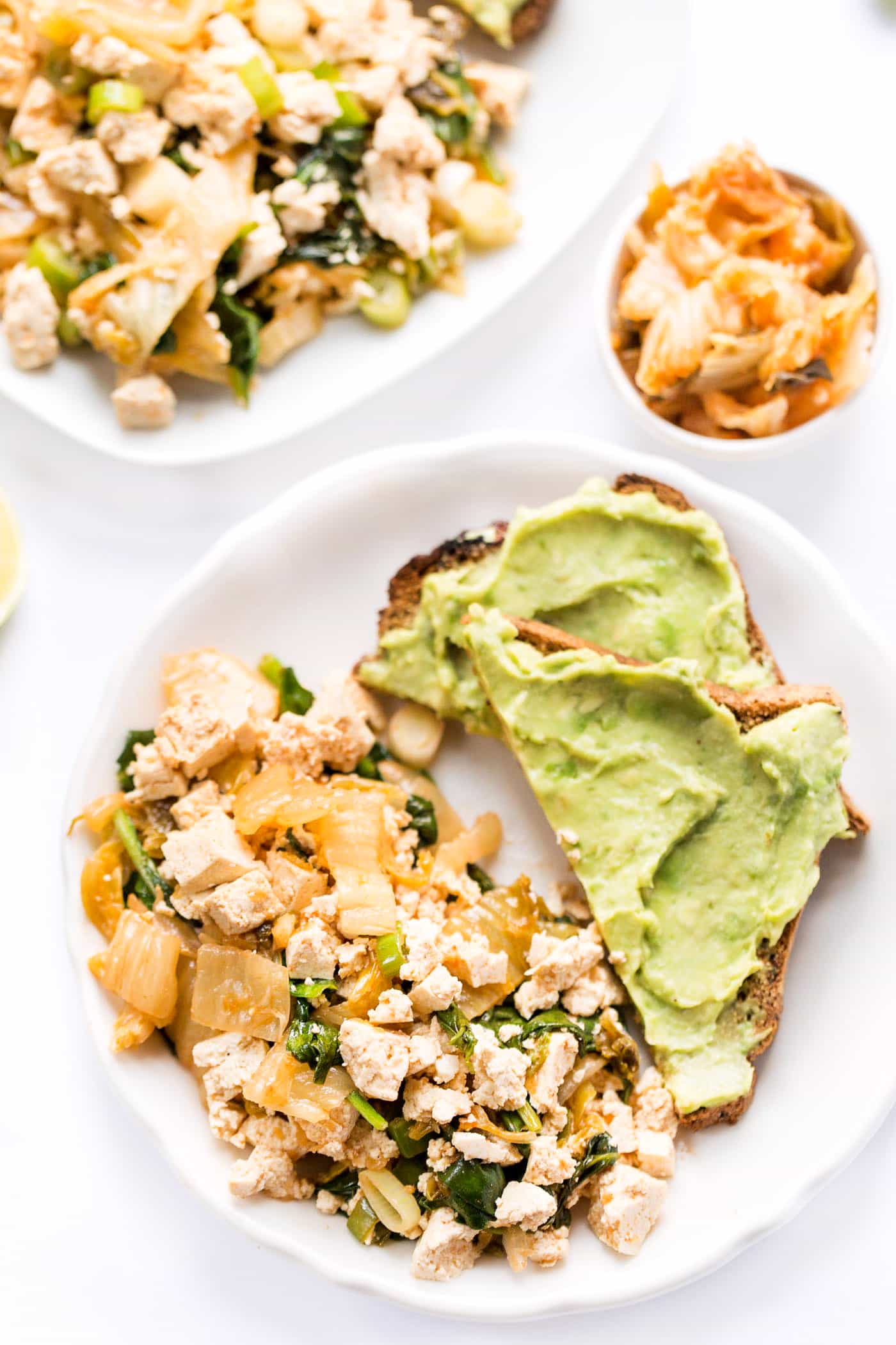 A plate of tofu and kimchi with two slices of avocado toast