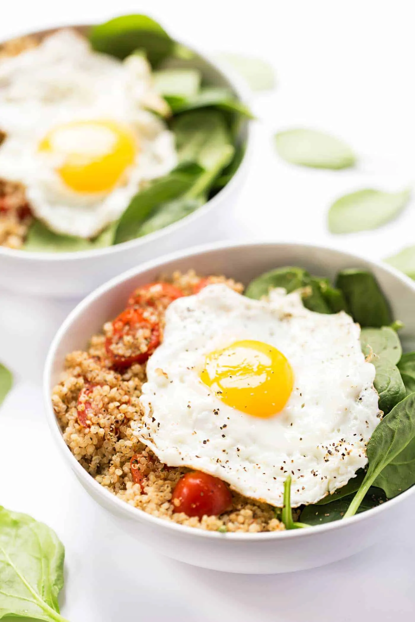 Savory Breakfast Quinoa Bowls with spinach, tomatoes and fried eggs on top!