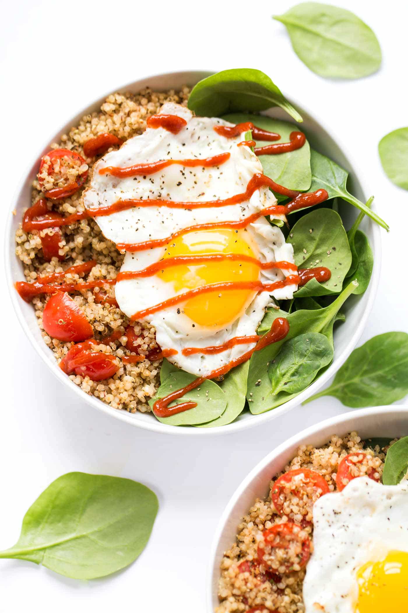 This 5-minute savory breakfast quinoa recipe with hints of garlic, cherry tomatoes, and a fried egg is a game-changing vegetarian breakfast. Overhead photo of savory breakfast quinoa with a runny fried egg on top.