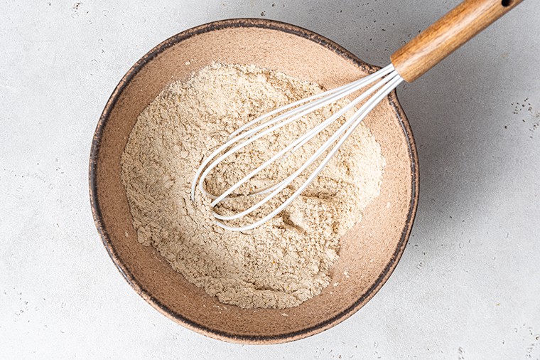 A brown bowl with almond flour and a whisk