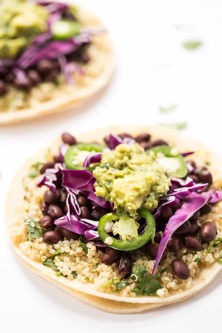 close up on a cilantro lime black bean taco with quinoa, jalapenos, guacamole and red cabbage