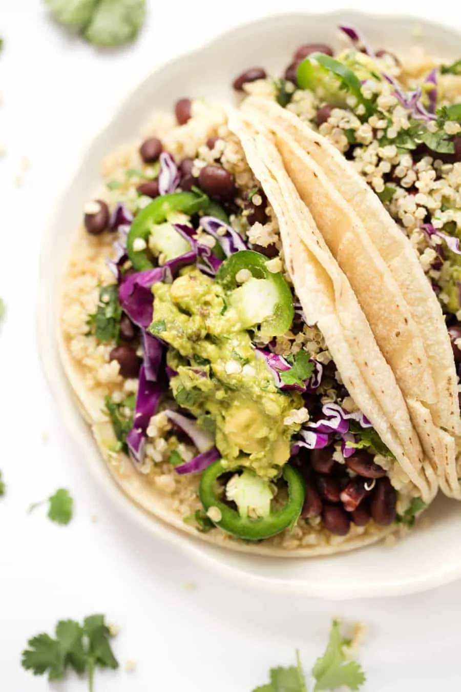 overhead of a white plate with cilantro lime tacos topped with guacamole