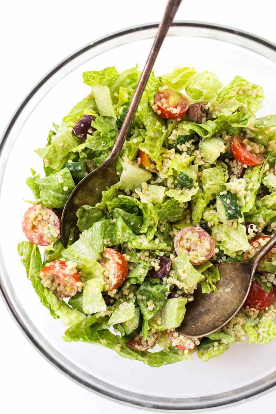 Mediterranean Quinoa Salad with chopped romaine, cherry tomatoes, cucumbers, olives and a creamy herbed tahini dressing!