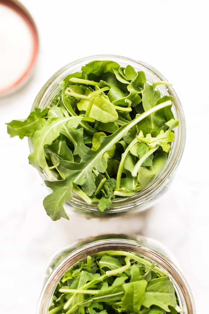 Salad greens sprout out of the top of a mason jar. 