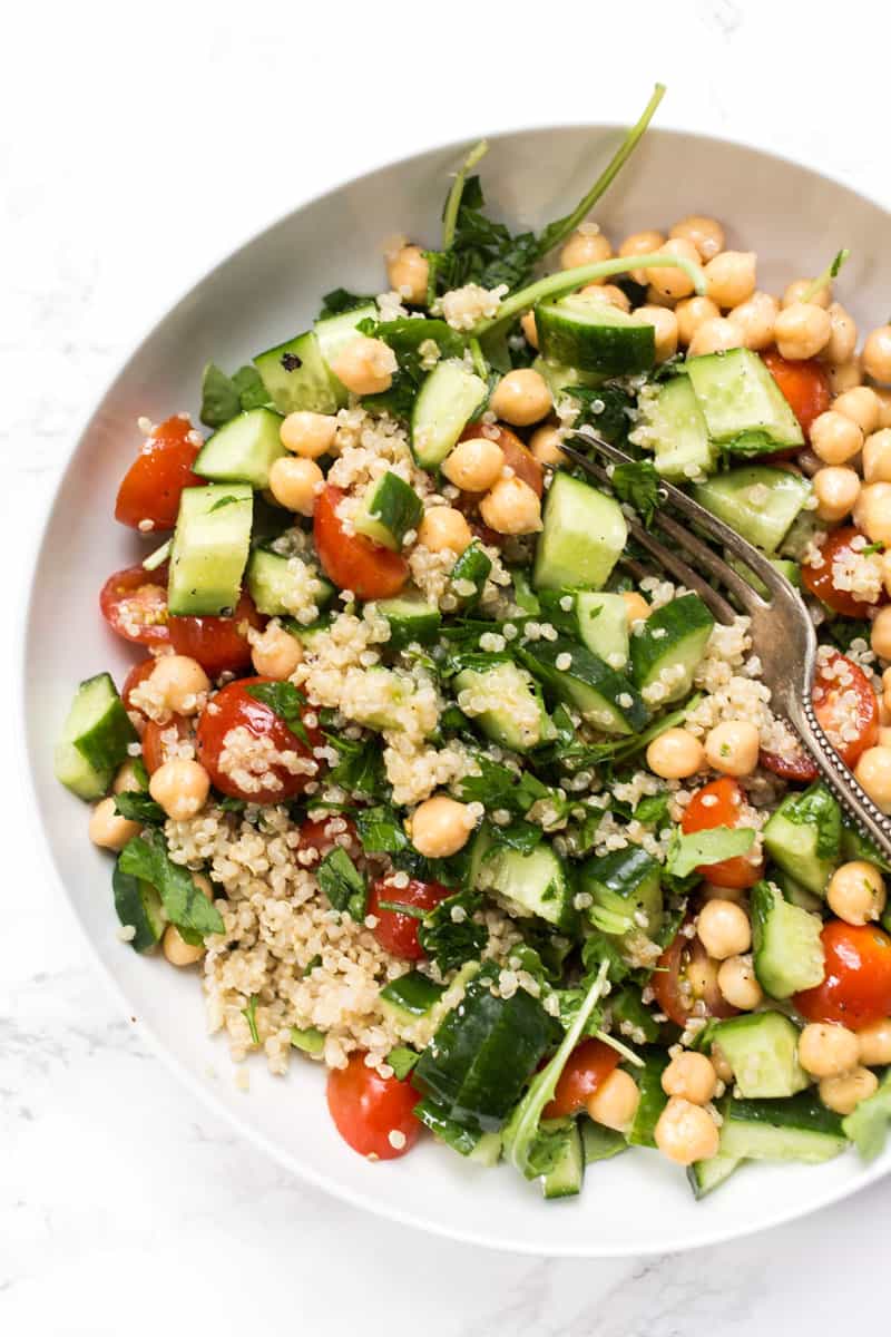 A mason jar salad with lemon-mustard dressing, chickpeas, veggies and quinoa on a white plate. 