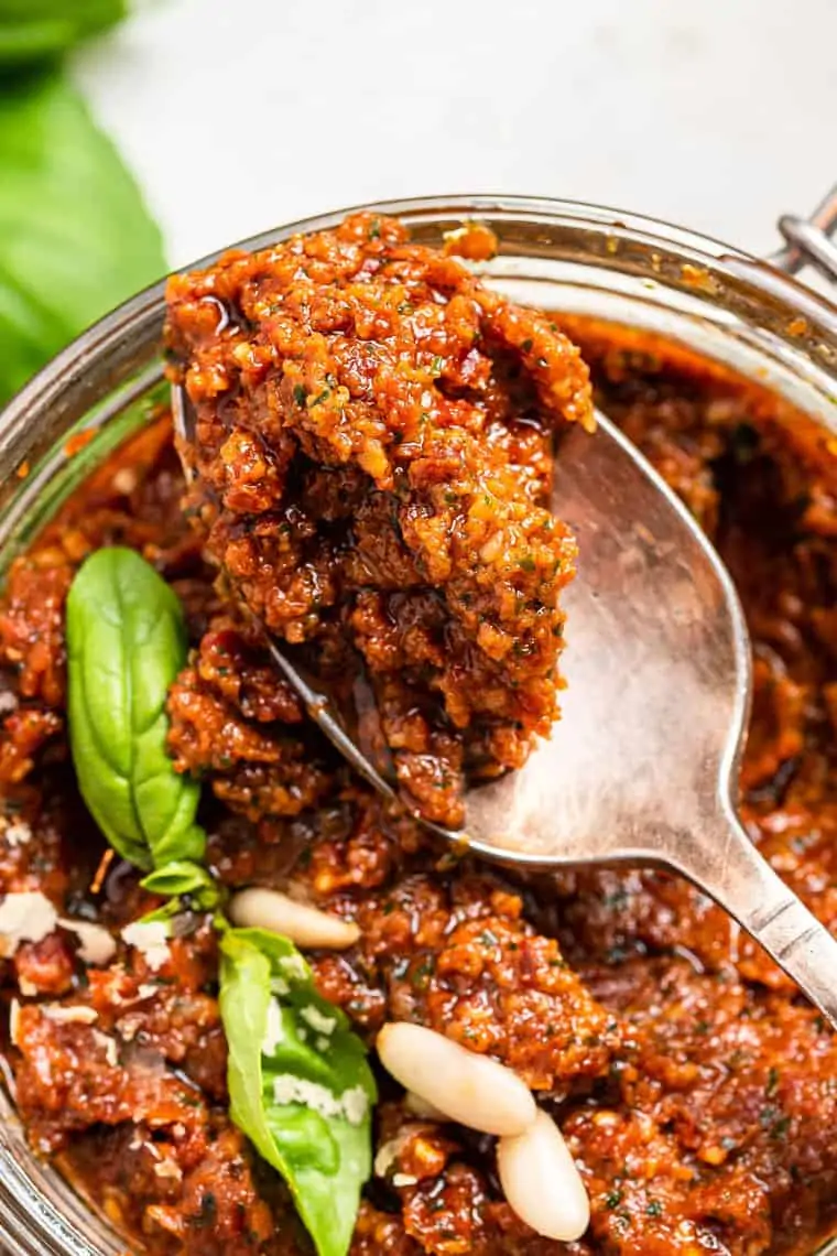 close up on a jar of sun dried tomato pesto with basil