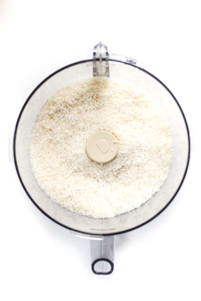 Overhead view of shredded coconut sitting in a food processor