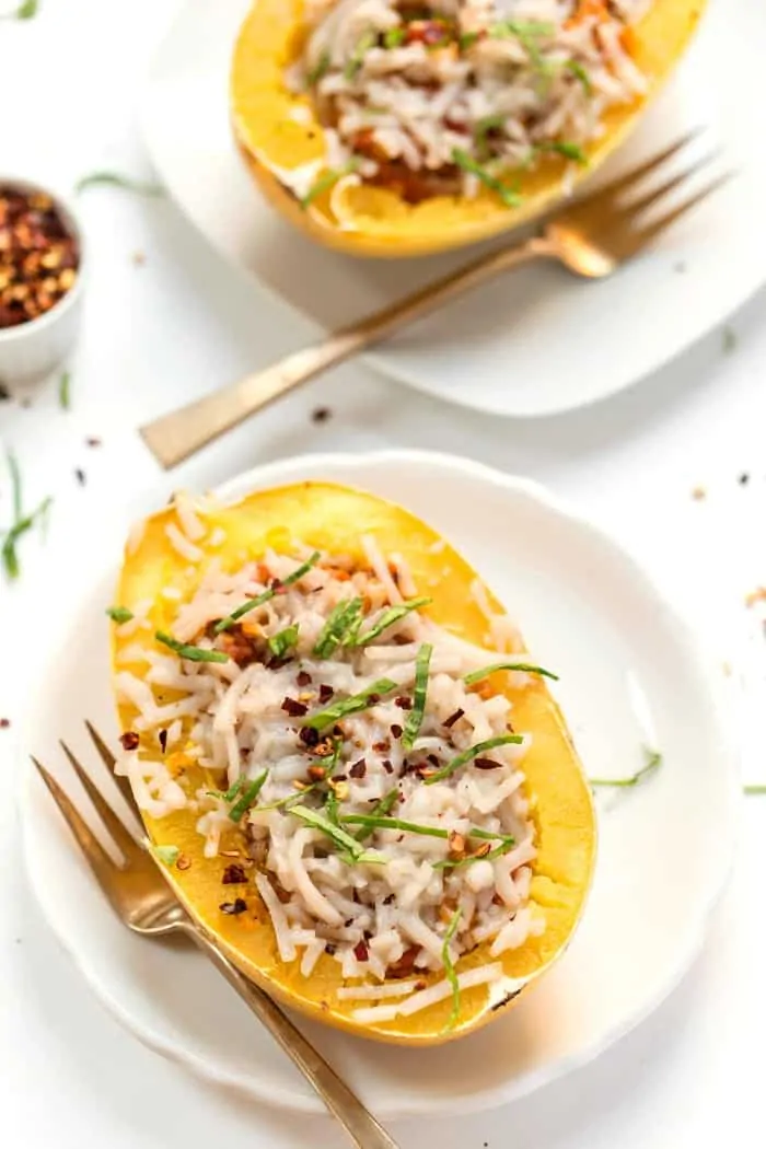 Overhead view of two spaghetti squash boats served on plates next to forks.