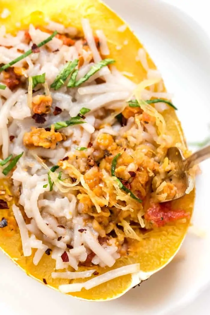 Close up overhead view of a fork tucked into vegan bolognese inside a spaghetti squash boat.