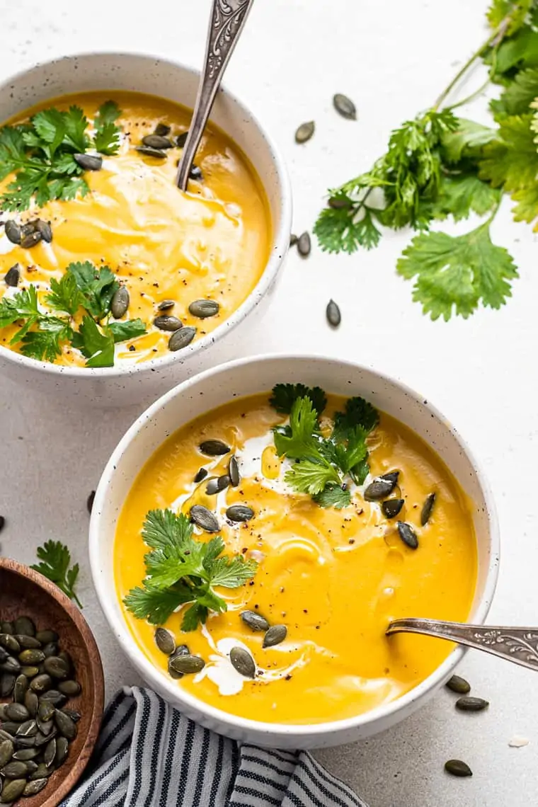 bowls of curried cauliflower and acorn squash soup with pumpkin seeds