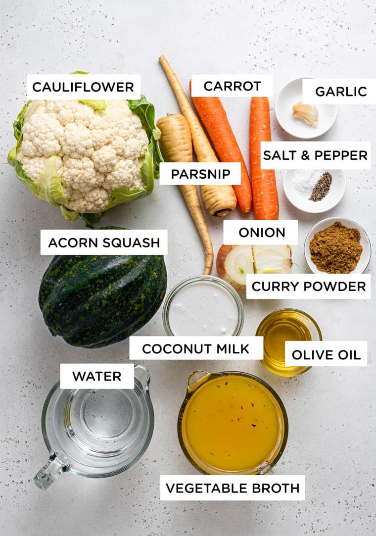 This curried acorn squash soup recipe is cozy and creamy, packed with roasted cauliflower, veggies, and spices. Vegan and freezer-friendly! Overhead view of ingredients for curried cauliflower and acorn squash soup.