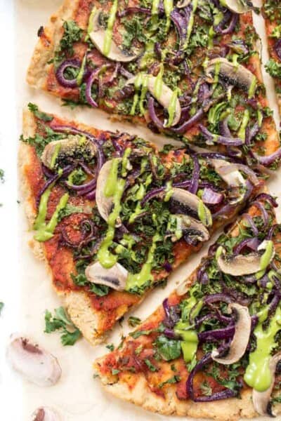 Overhead view of vegan pizza topped with kale, caramelized onions, and mushrooms