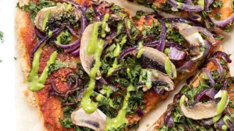 Overhead view of vegan pizza topped with kale, caramelized onions, and mushrooms