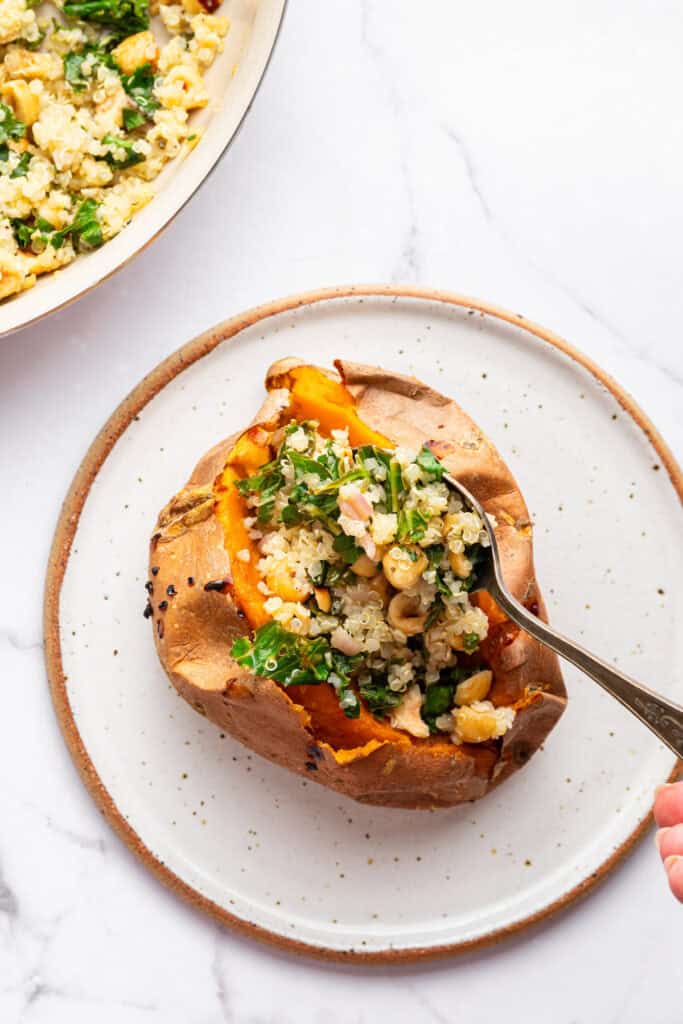These Stuffed Sweet Potatoes are filled with quinoa, kale and hazelnuts, then topped with creamy tahini sauce. A hearty main or side dish! Spoon stuffing quinoa, hazelnuts, and kale mixture into sweet potato.