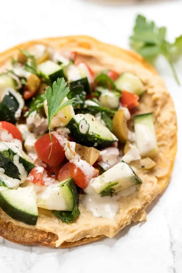 vegan tostadas topped with a hummus and a mediterranean salad