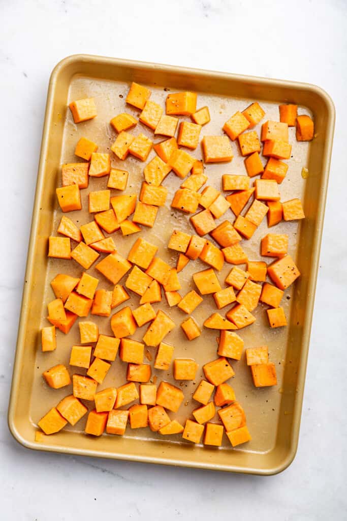 Overhead view of sweet potatoes tossed with oil, salt, and pepper