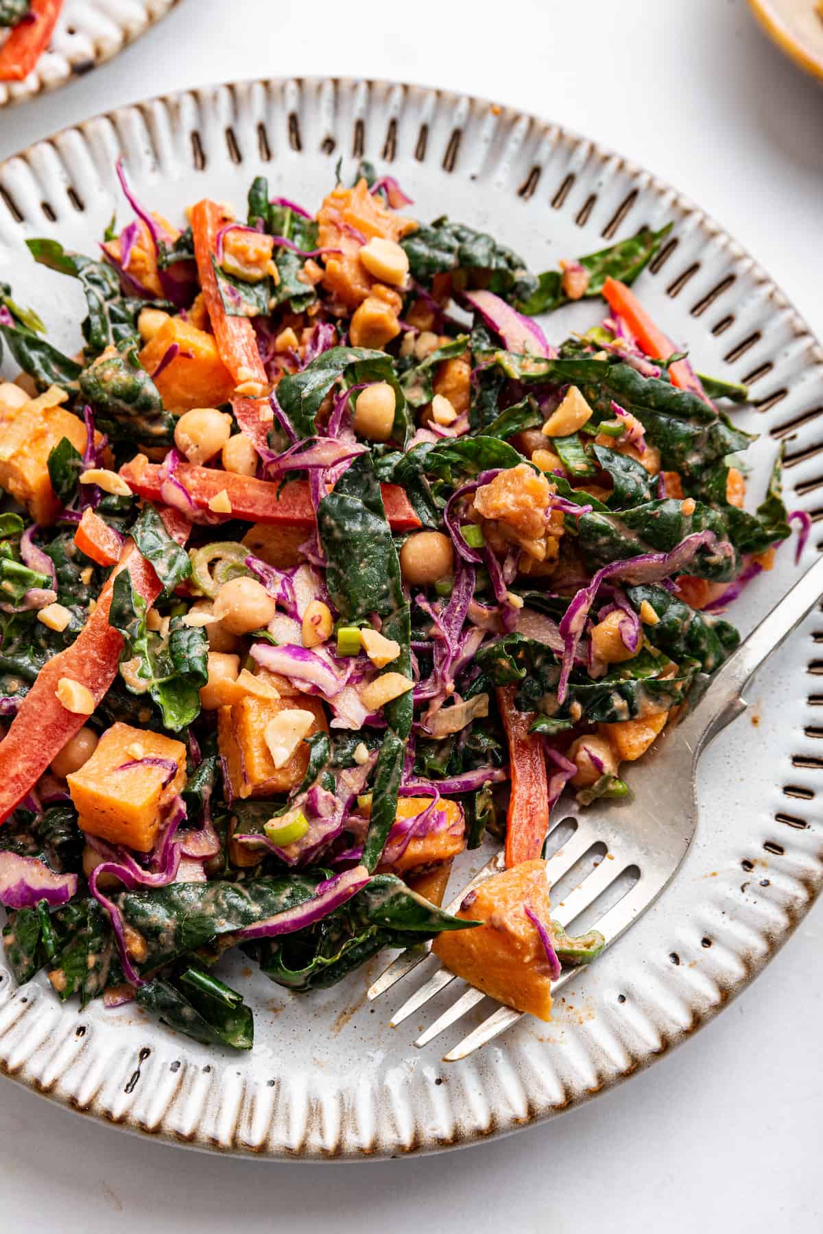 Kale sweet potato salad pairs tender roasted sweet potatoes with kale and chickpeas, then tosses it all in a creamy Thai-inspired dressing! Overhead view of kale sweet potato salad on plate