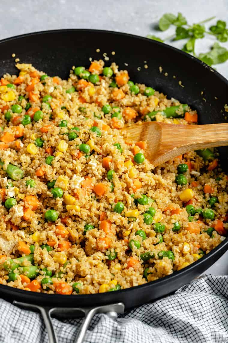 cooking quinoa fried rice with vegetables in a cast iron pan