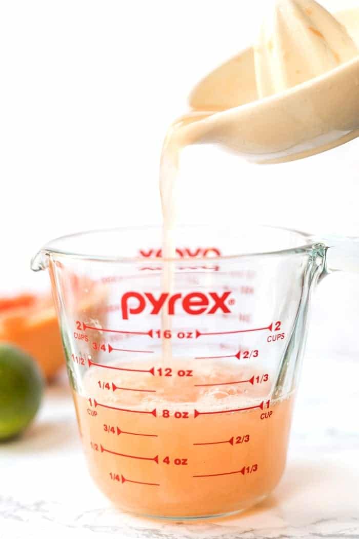 These Healthy Grapefruit Margaritas use just 4 ingredients and have no added sugar! They're a refreshing twist on the skinny margarita! Pouring grapefruit juice into measuring cup