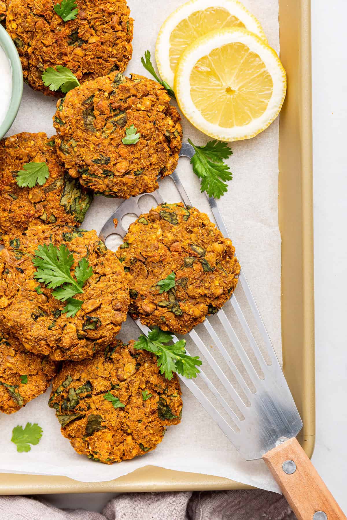 Spatula scooping lentil patty from sheet pan