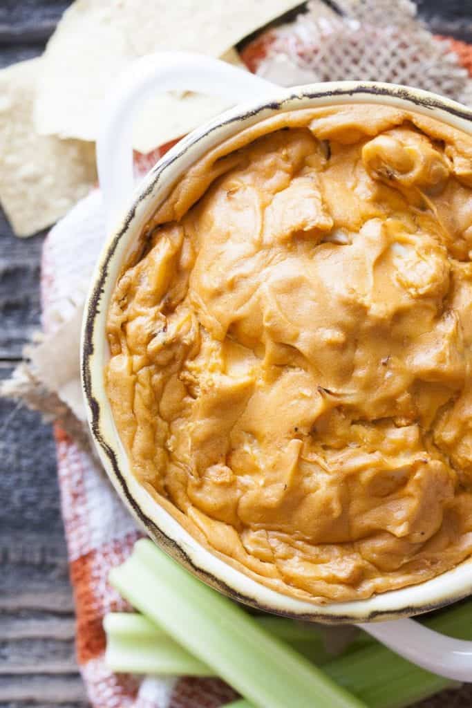 Vegan Buffalo Cauliflower Dip served in white bowl with celery sticks