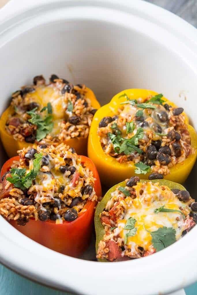 four stuffed peppers in a white dish with cheese on top