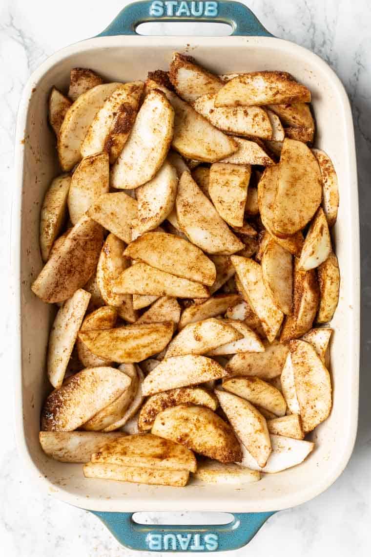 A baking dish filled with season, uncooked apple slices for gluten-free apple crisp