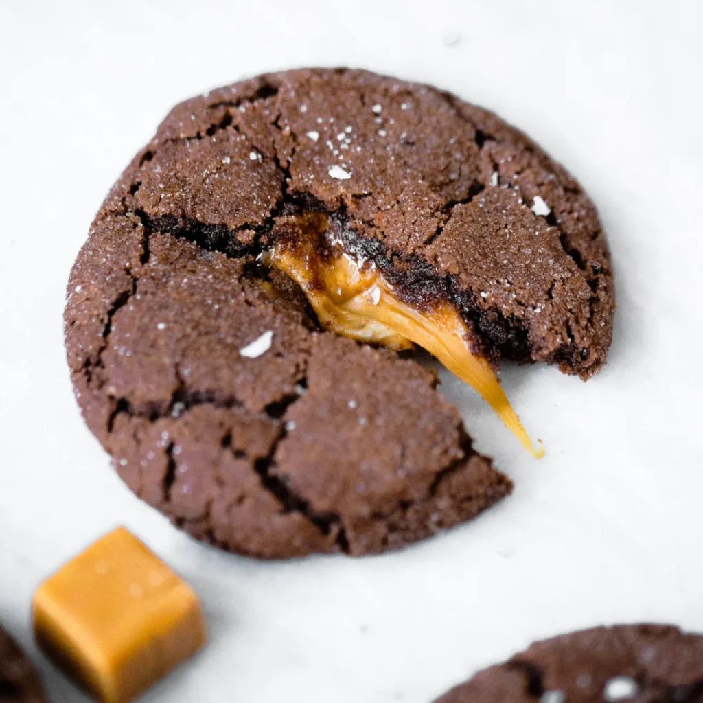 dark chocolate cookie broken open with melted caramel coming out