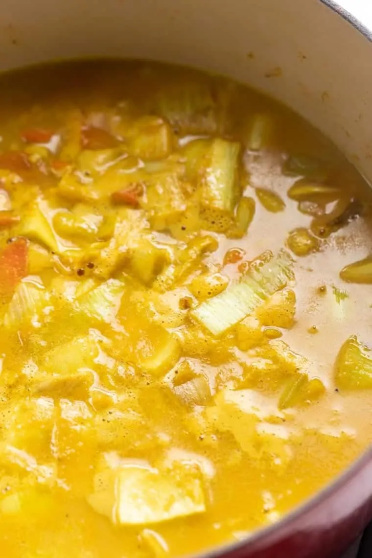 Close up of turmeric carrot soup cooking in a pot. 