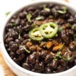 Bowl of Instant Pot black beans with jalapeño slices on top