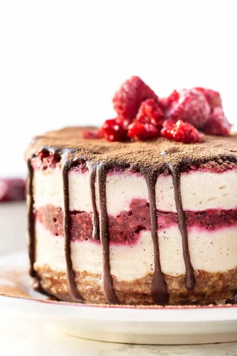 This mini no bake raspberry cheesecake is an easy dessert with creamy vegan cheesecake layers and sweet raspberry filling. Gluten-free, too! A mini no bake raspberry cheesecake topped with a drip of chocolate ganache, garnished with fresh raspberries.