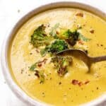 Spoon going into bowl of vegan creamy broccoli soup