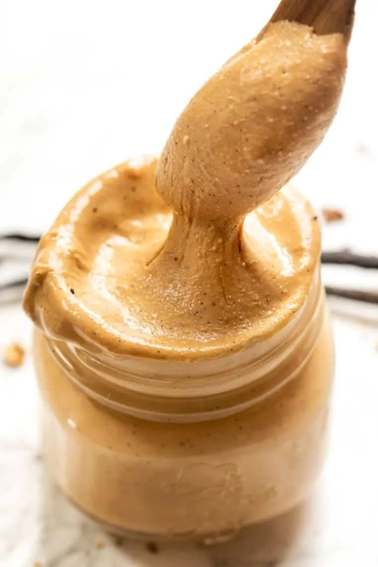 Overhead view of a jar of vanilla bean cashew butter with a spoon pulling out a spoonful