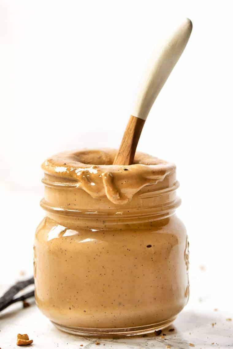 A small jar of cashew butter with a wooden spoon in it