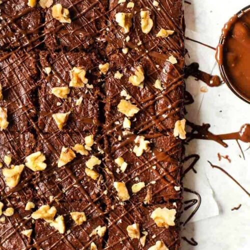 Overhead view of cut almond butter brownies topped with walnuts and chocolate drizzle