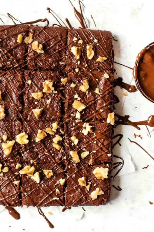 Overhead view of cut almond butter brownies topped with walnuts and chocolate drizzle