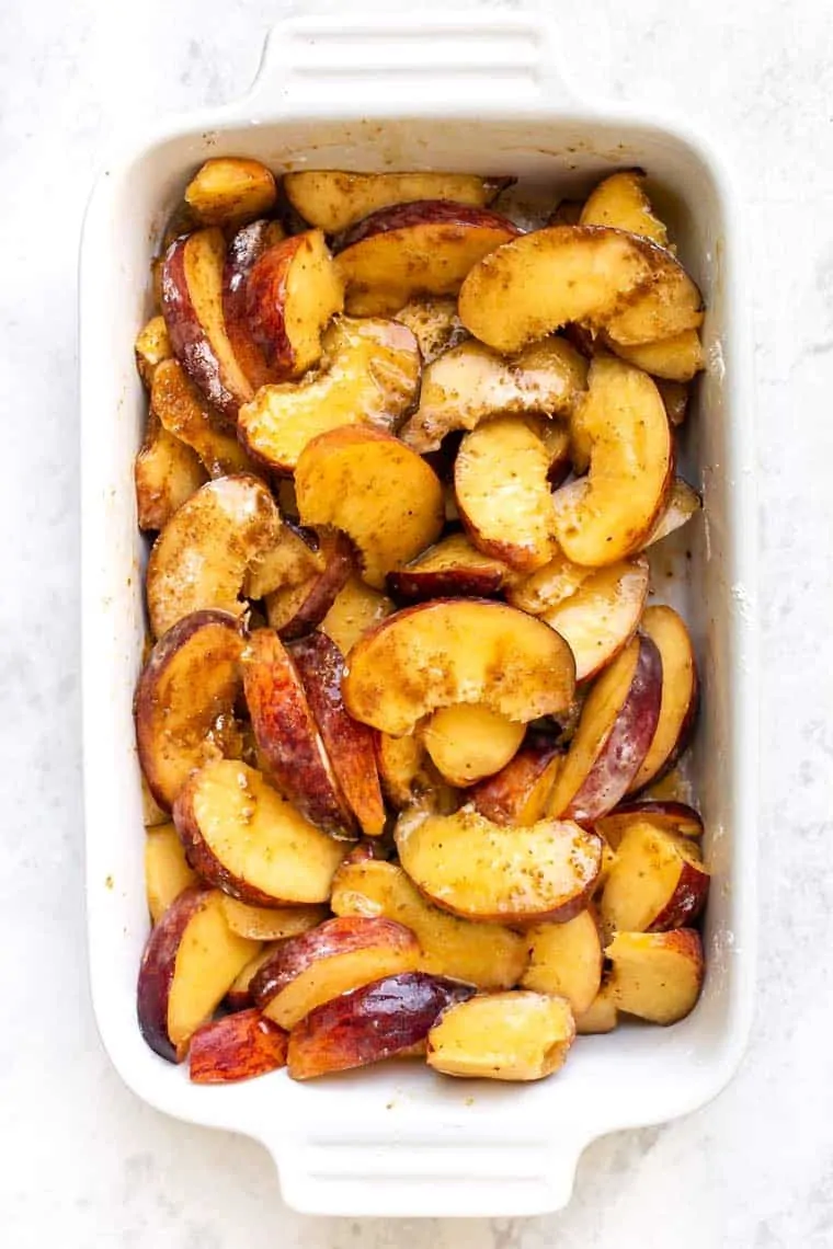 Overhead view of peaches covered in sugar in a baking dish