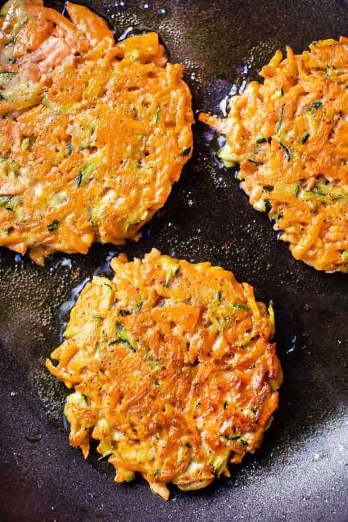 These gluten-free veggie fritters are crispy, tender and packed with sweet potato, carrots and zucchini for a quick, healthy side or snack! Frying veggie fritters in skillet.