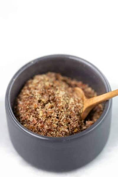 Flaxseed and water in a bowl with a wooden spoon.
