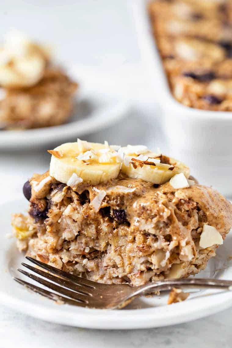 Slice of protein baked oatmeal on plate, topped with bananas and coconut