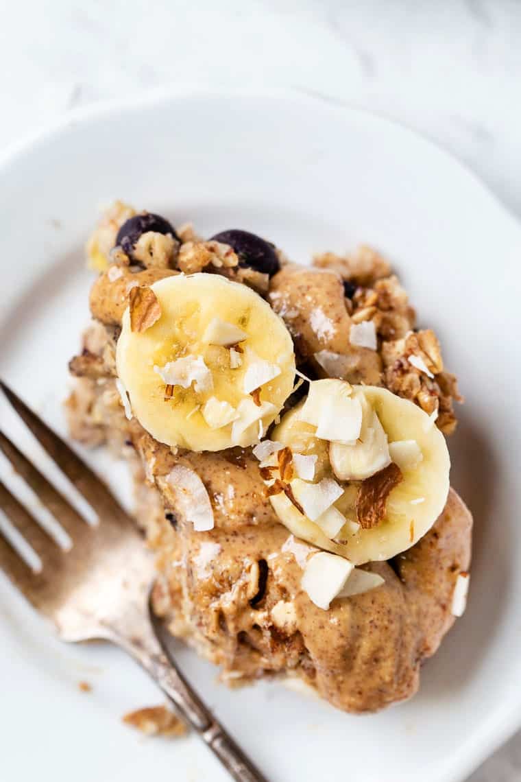 This healthy protein baked oatmeal recipe is gluten-free, vegan and packed with plant protein. Naturally sweetened and full of fresh fruit! Overhead view of protein baked oatmeal on plate with fork