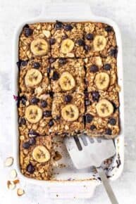 Overhead view of banana blueberry baked oatmeal in baking dish with spatula