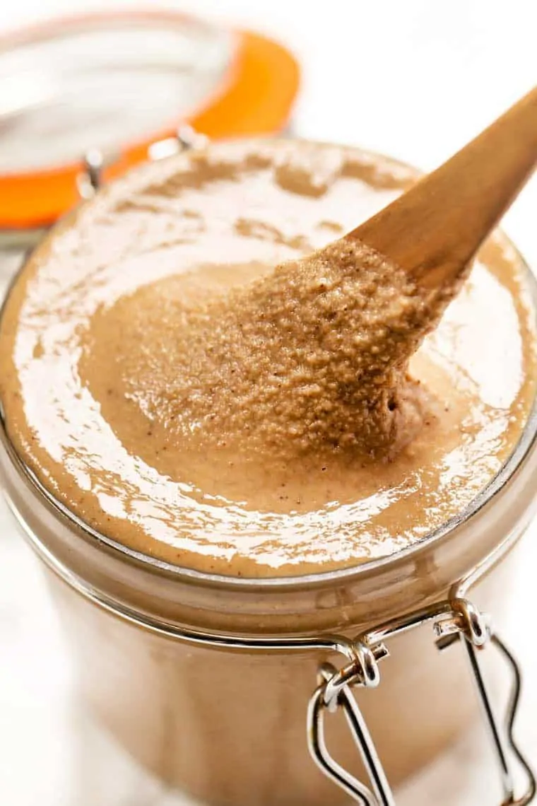 Closeup view of homemade tahini in jar with spoon